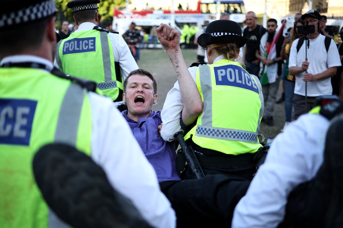 الشرطة البريطانية خلال اعتقالها شاباً مشاركاً في المظاهرة (أ ف ب)