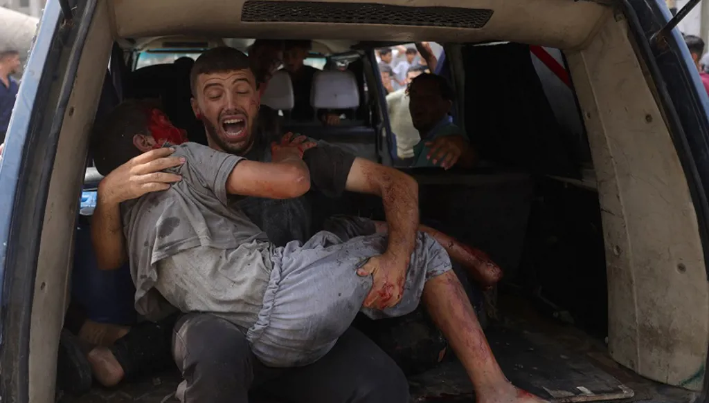 رجل فلسطيني يحمل شابا مصابا في غزة (ا ف ب)