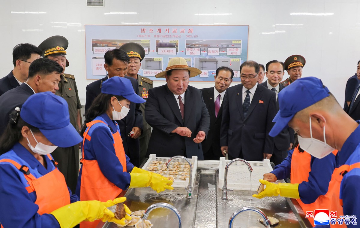 كيم جونغ أون مع العاملين في المصنع (أ ف ب).