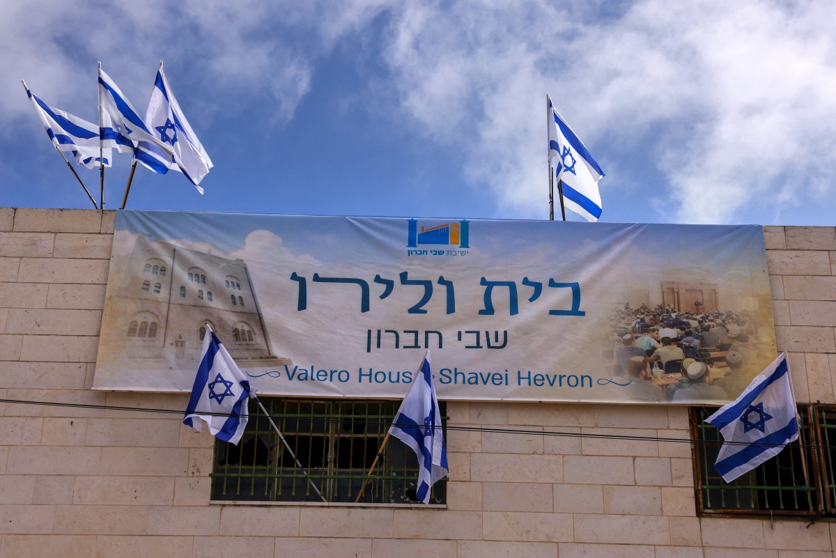 أعلام إسرائيلية ولافتة عند مدخل السوق الفلسطيني في البلدة القديمة من الخليل (أ ف ب). 