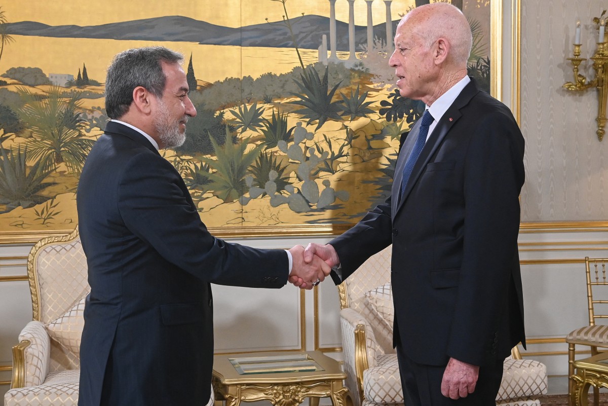 الرئيس التونسي قيس سعيد مصافحاً وزير الخارجية الإيراني عباس عراقجي.(أف ب)