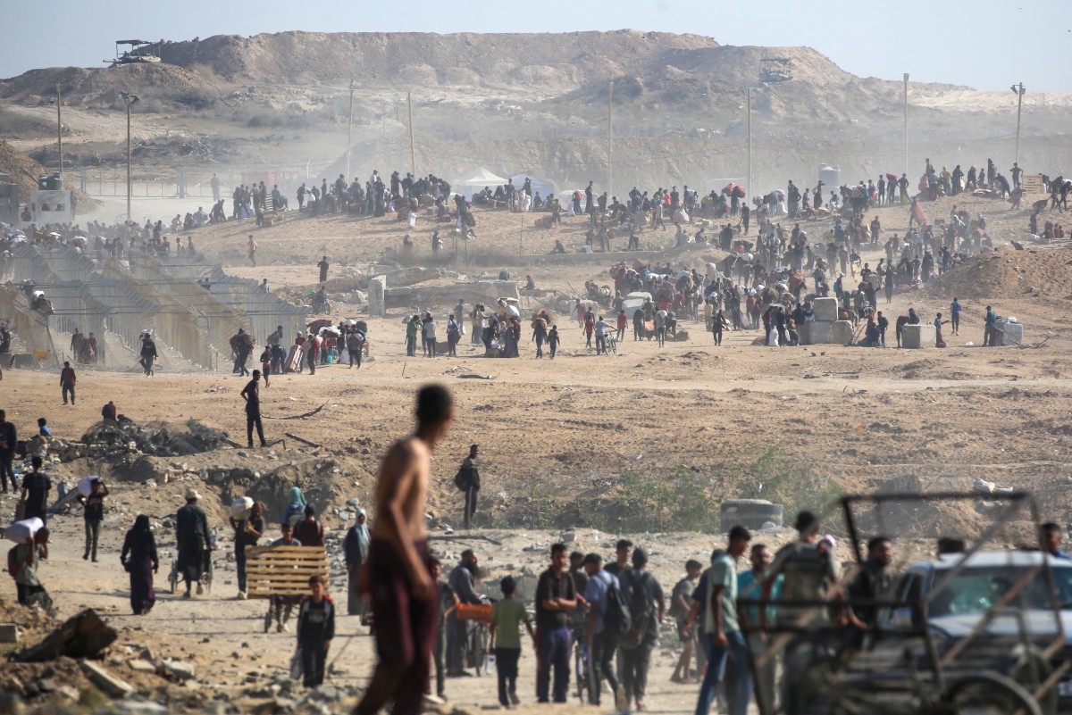 يسير الناس حاملين أكياس المساعدات الإنسانية التي تلقوها في مركز توزيع تديره مؤسسة غزة الإنسانية المدعومة من الولايات المتحدة وإسرائيل، في ما يسمى ممر نتساريم (أ ف ب)