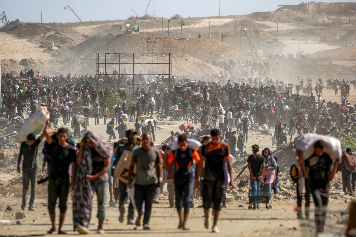 أشخاص يحملون طرود المساعدات الإنسانية التي حصلوا عليها من مركز توزيع تديره مؤسسة غزة الإنسانية.  (أ ف ب)