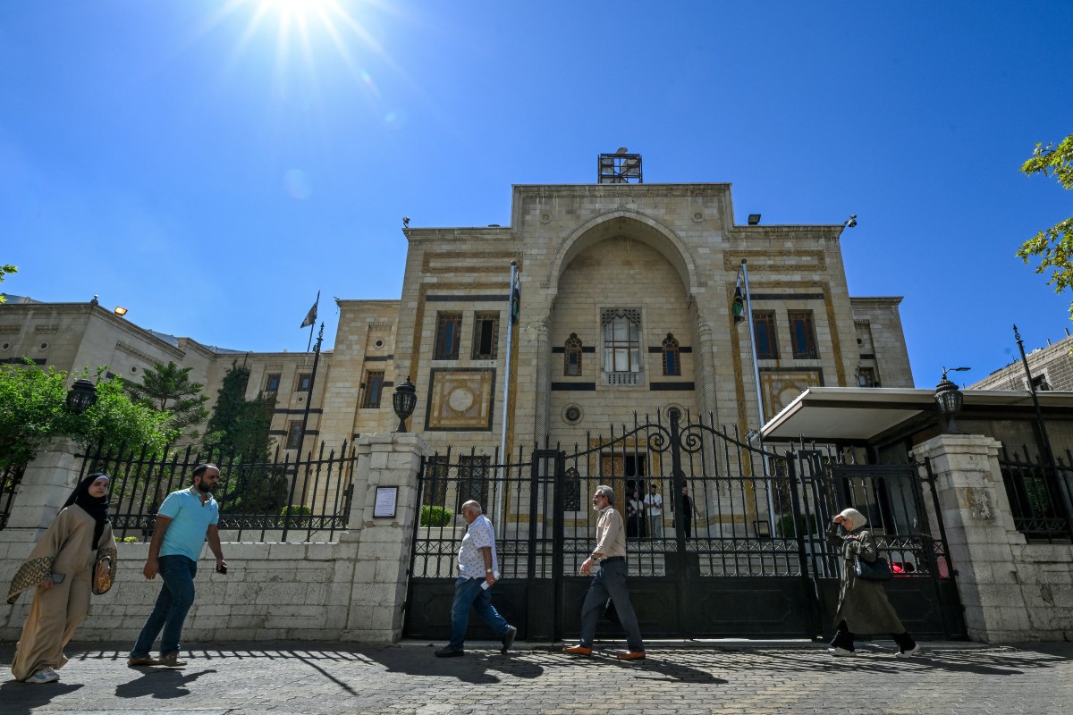 أشخاص يمرون أمام مبنى البرلمان في دمشق. (أ ف ب)