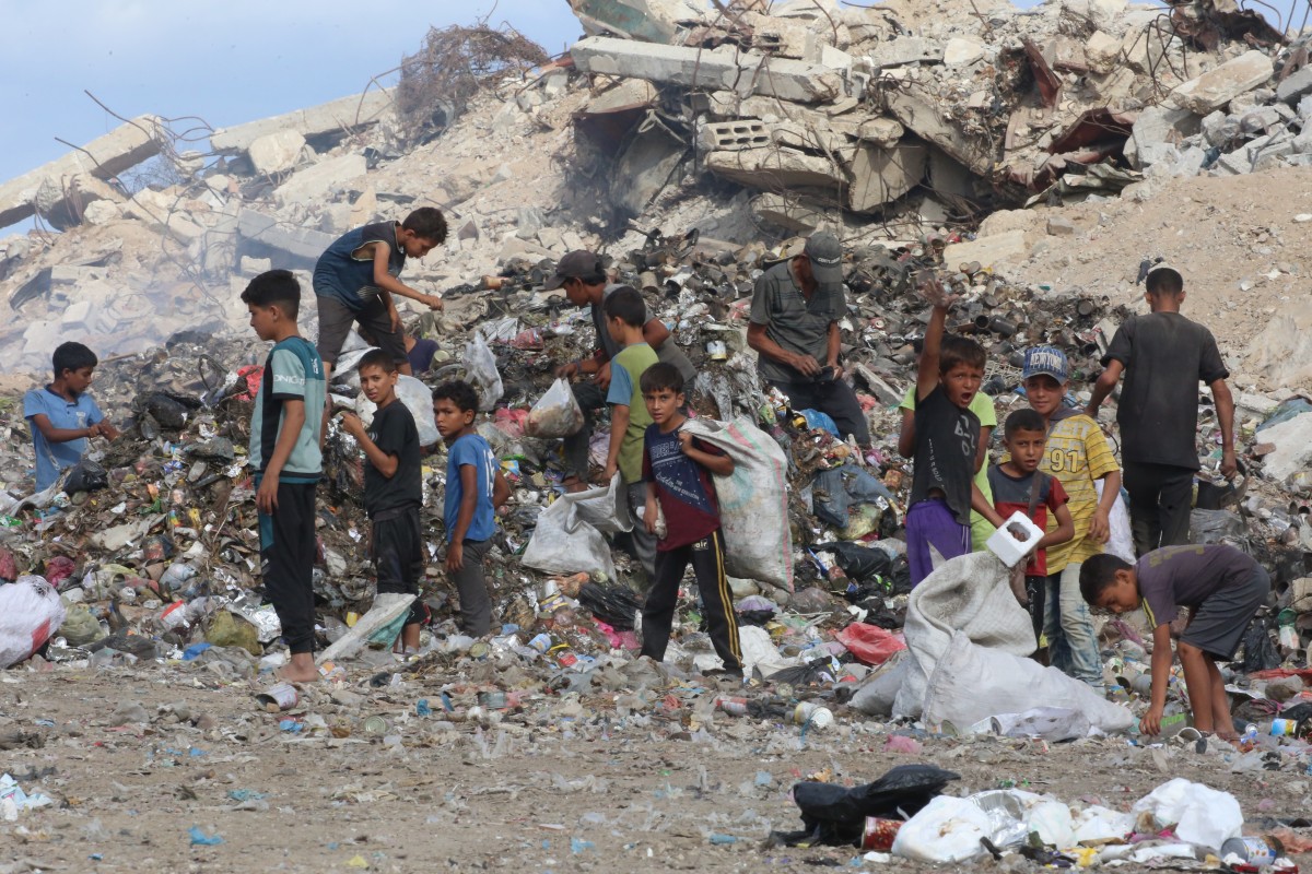 أطفال فلسطينيون نازحون يبحثون عن أشياء يمكن استخدامها كوقود للطهي وسط كومة من القمامة بجوار المباني المدمرة في مخيم البريج للاجئين في وسط قطاع غزة.  (أ ف ب)