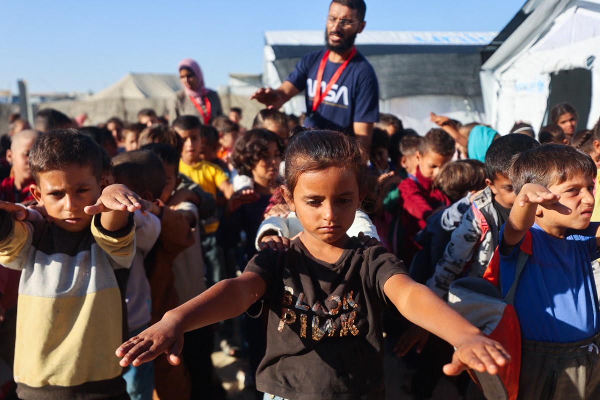 تلاميذ فلسطينيون يؤدون تمارين بدنية أثناء تجمعهم في ساحة مدرسة أنشأتها جمعية مياسم للثقافة بدعم من اليونيسف، قبل بدء الفصل الدراسي في مخيم للنازحين في منطقة القرارة في خان يونس. (أ ف ب) 