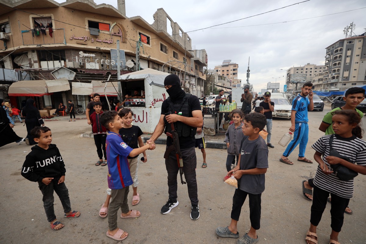 أحد أفراد قوات الأمن الداخلي التابعة لحركة حماس يحيي الأطفال في مخيم النصيرات للاجئين، وسط قطاع غزة. (أ ف ب)