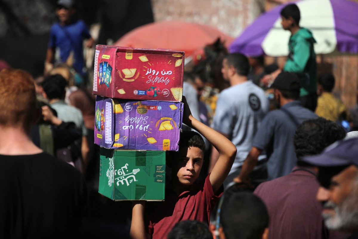 طفل فلسطيني يحمل صناديق البسكويت في أحد أسواق دير البلح في وسط قطاع غزة. (أ ف ب)