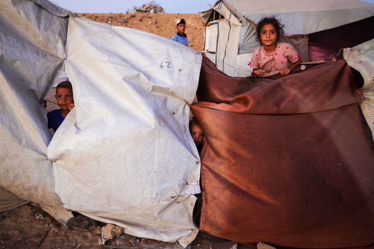 أطفال فلسطينيون يلتقطون صورة بالقرب من مأواهم المؤقت في خان يونس، جنوب قطاع غزة. (أ ف ب)