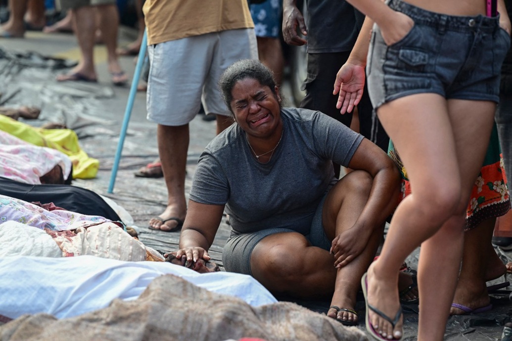  امرأة تبكي بجانب رجل ميت يرقد بين صف من الجثث في ساحة ساو لوكاس (أ ف ب)