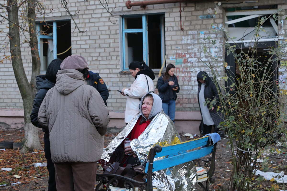 يقف السكان المحليون خارج مبنى متضرر في زابوريجيا (أ ف ب).