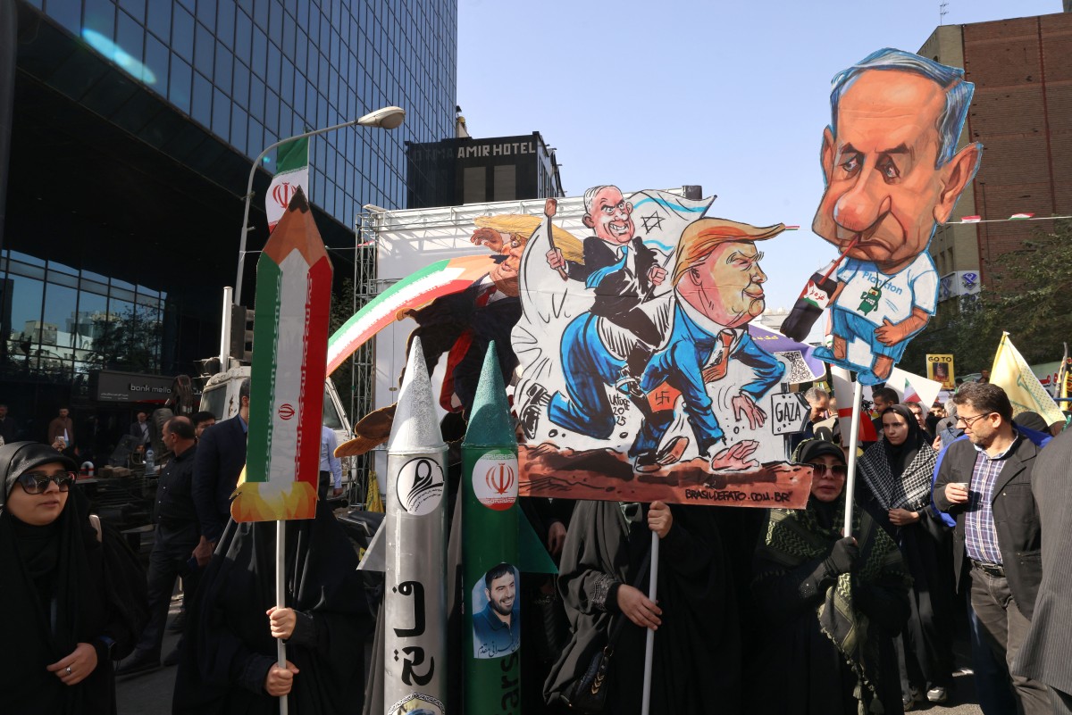 لافتات تحمل طابعاً ساخراً من ترامب ونتنياهو خلال تظاهرة في طهران. (أ ف ب)