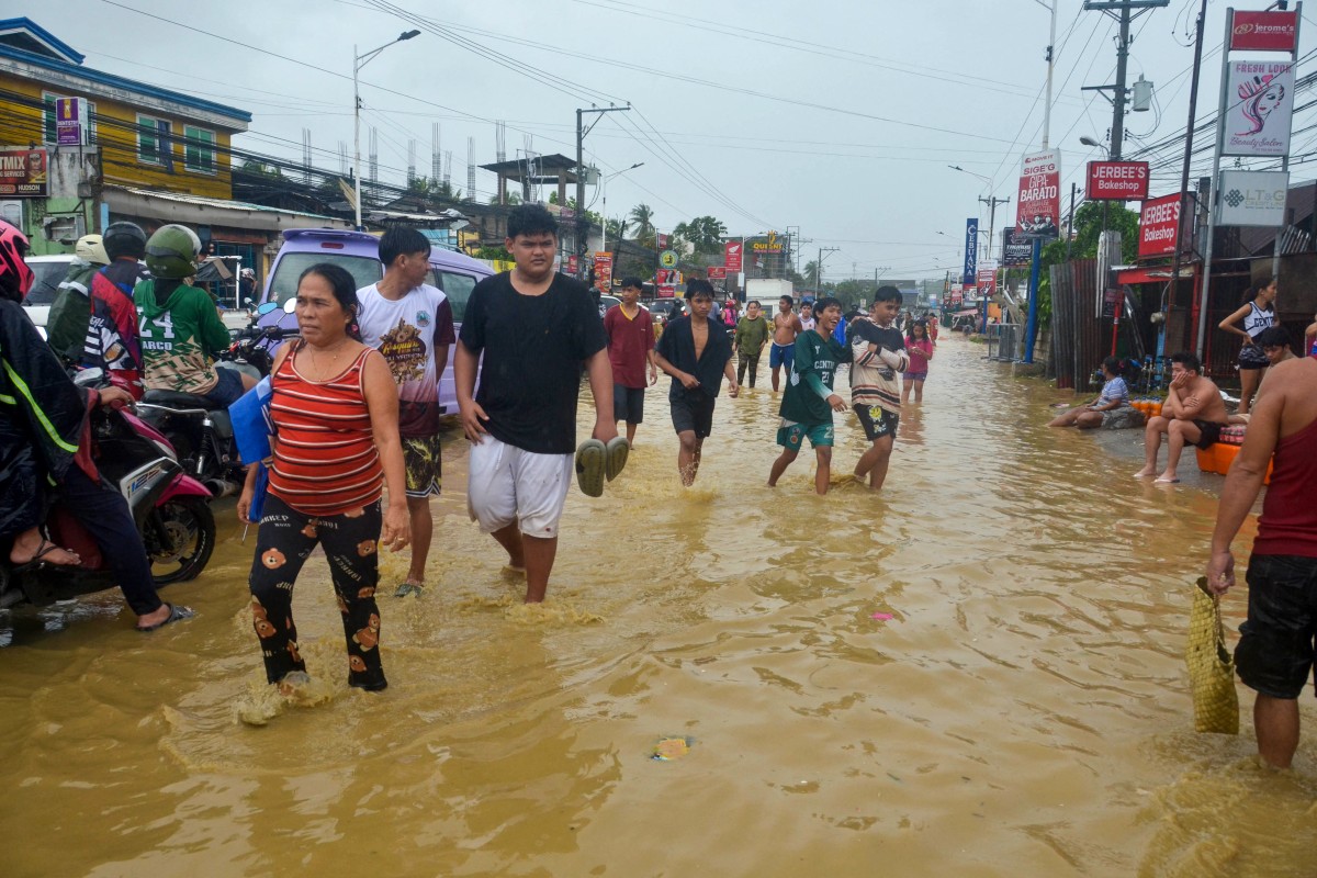 يخوض السكان في شارع غمرته المياه في بلدة ليلوان، مقاطعة سيبو. (أ ف ب)