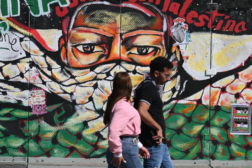 مارة أمام جدارية رسمها في مكسيكو سيتي (أ ف ب)