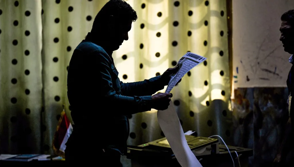 ضابط أمن عراقي ينظر إلى بطاقة اقتراعه قبل الإدلاء بصوته قبل الانتخابات البرلمانية في 11 نوفمبر، في مدينة البصرة الجنوبية (أ ف ب)