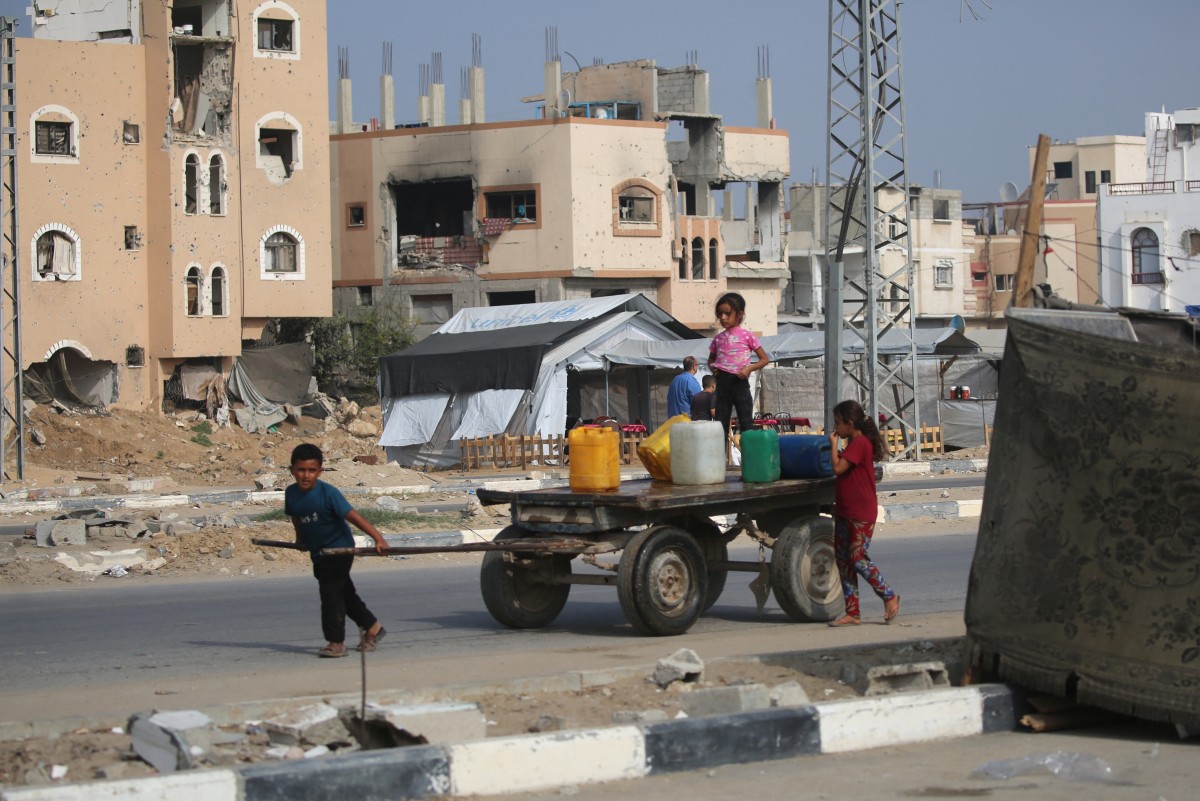 طفل فلسطيني يجرّ عربة محملة بالمياه بالقرب من مخيم النصيرات للاجئين وسط قطاع غزة. (أ ف ب)