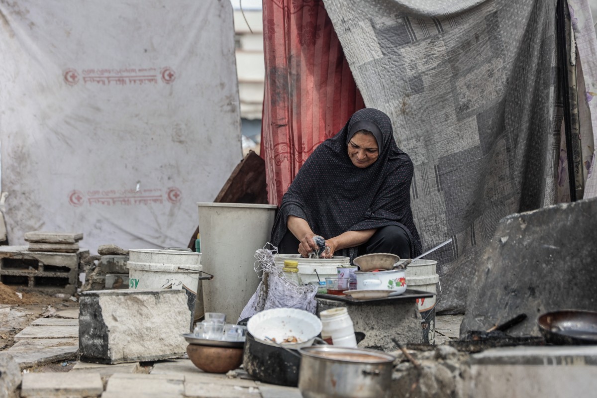 امرأة فلسطينية تغسل الملابس في مخيم للنازحين في مدينة غزة في 14 نوفمبر 2025. (أ ف ب)