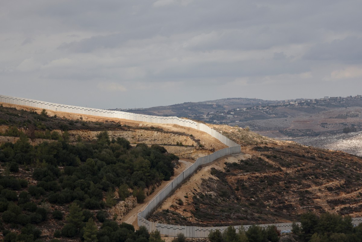 الجدار الحدودي مع ظهور قرية عين إبل اللبنانية في الخلفية. (أ ف ب)