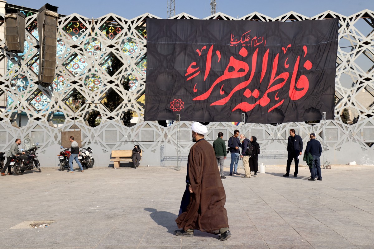 رجل دين يمر بجدارية كتب عليها فاطمة الزهراء في طهران.(أف ب)