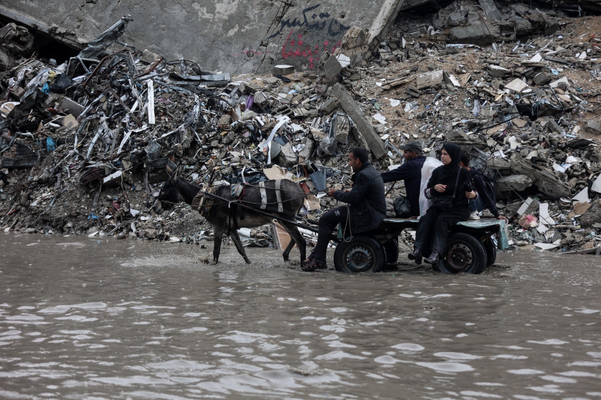 رجل يسير وسط مياه الفيضانات في مخيم مؤقت يأوي الفلسطينيين النازحين بعد هطول أمطار غزيرة في مدينة غزة. (أ ف ب)