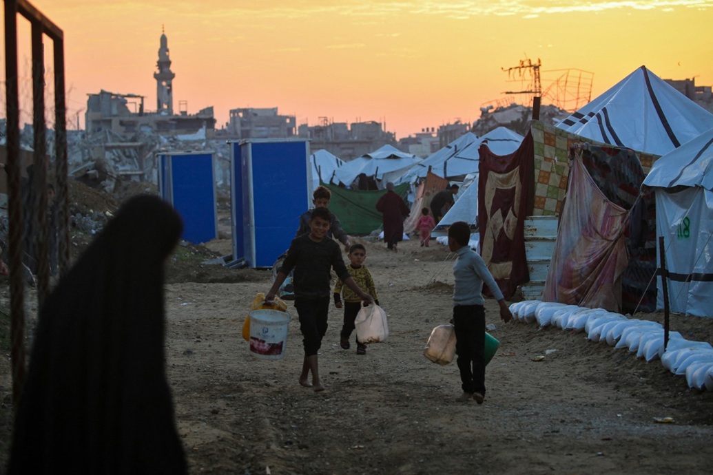 أطفال يحملون المياه في مخيم النصيرات للاجئين الفلسطينيين في وسط قطاع غزة (أ ف ب)