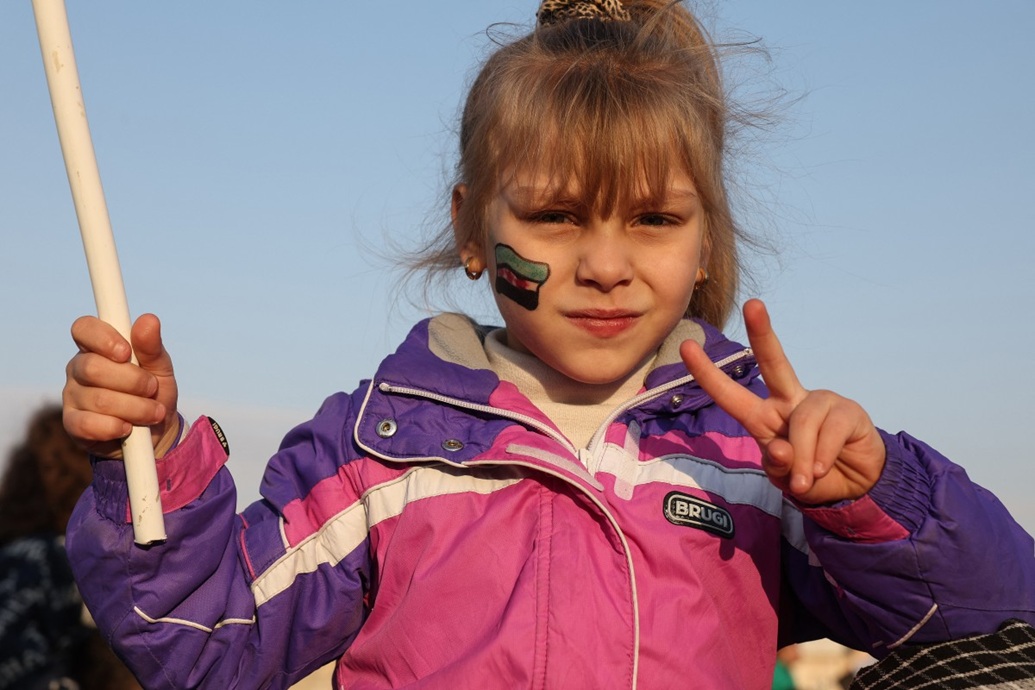 فتاة وجهها مطلي بألوان العلم السوري ترفع إشارة النصر خلال الاحتفالات (أ ف ب)