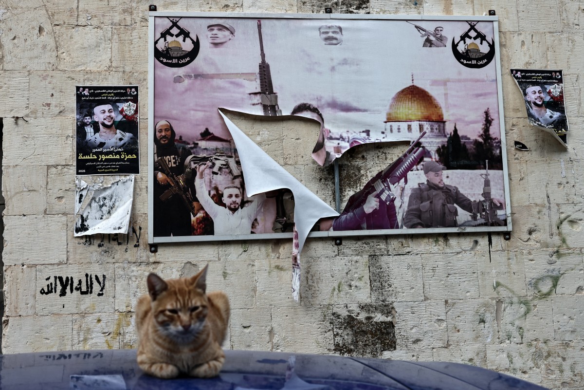 ملصق لمقاتلين فلسطينيين قتلى تمزق خلال غارة إسرائيلية في البلدة القديمة في نابلس، بالضفة الغربية. (أ ف ب)