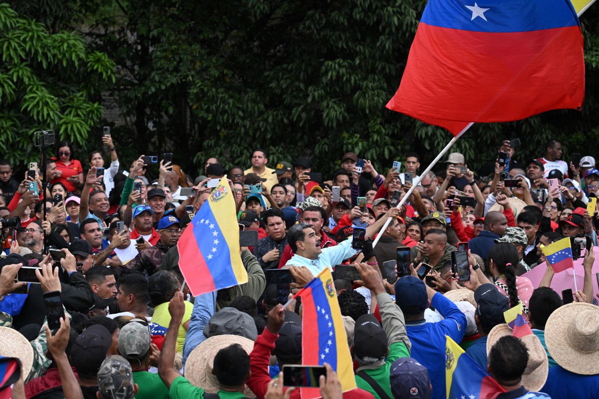 الرئيس الفنزويلي نيكولاس مادورو (في الوسط) يلوّح بالعلم الوطني لدى وصوله إلى تجمع لإحياء ذكرى معركة سانتا إينيس. (أ ف ب)