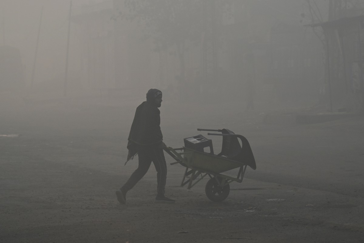 عامل يعبر الطريق وسط ضباب كثيف في لاهور. (أ ف ب)