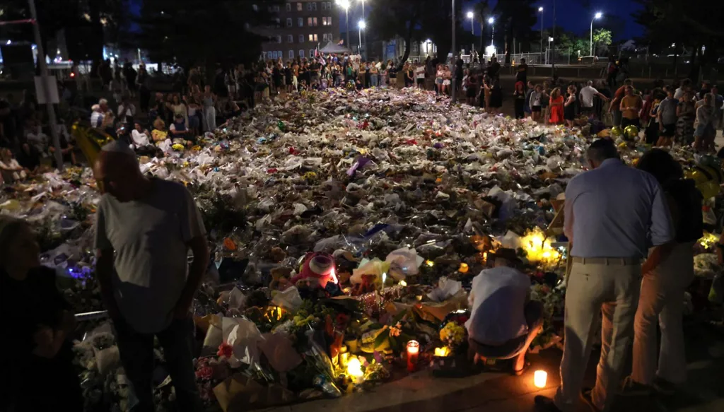 يتجمع المشيعون بجانب الزهور الموضوعة تكريماً لضحايا حادث إطلاق النار في شاطئ بوندي، في سيدني في 20 ديسمبر 2025. (أ ف ب)