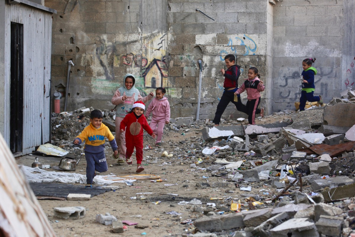 أطفال فلسطينيون يلعبون بجوار أنقاض المباني المدمرة في مخيم جباليا للاجئين، شمال قطاع غزة. (أ ف ب)