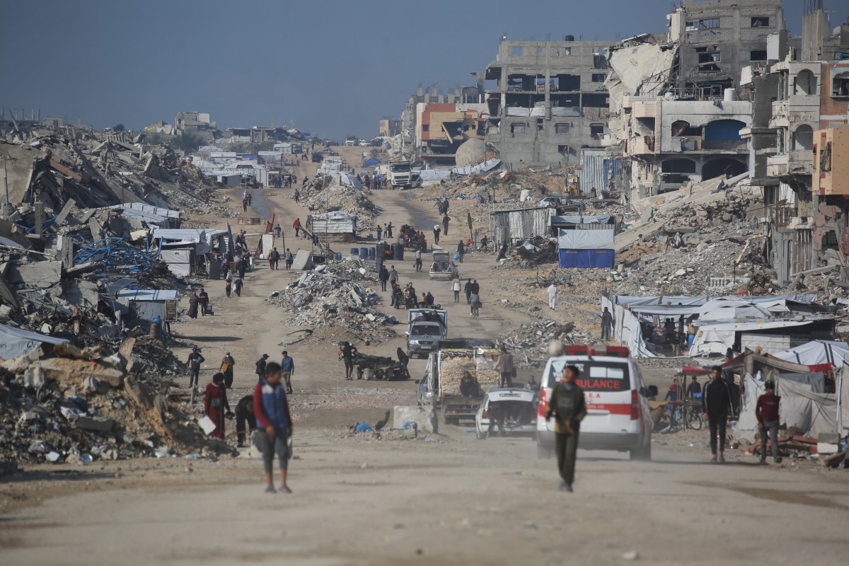 يسير الفلسطينيون في شارع بجوار أنقاض المباني المدمرة في مخيم جباليا للاجئين، شمال قطاع غزة. (أ ف ب )