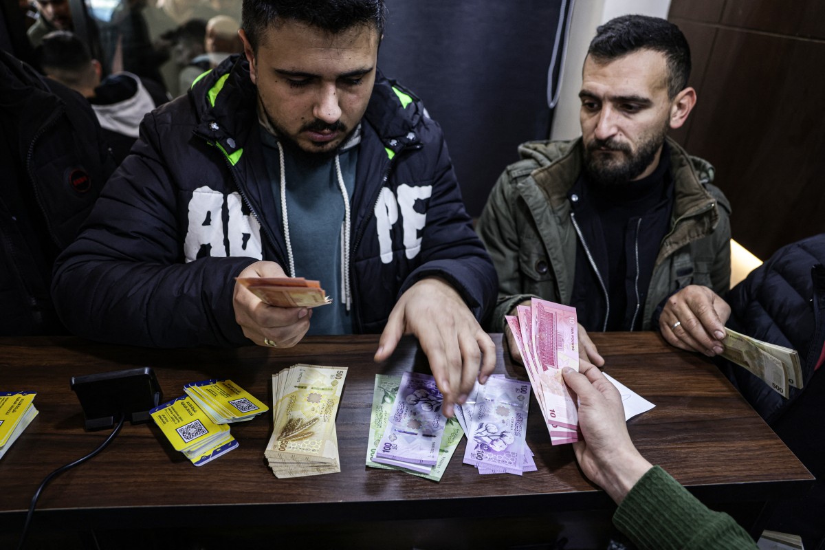 مواطن سوري يستبدل أوراقاً نقدية قديمة بأخرى جديدة. (أ ف ب)