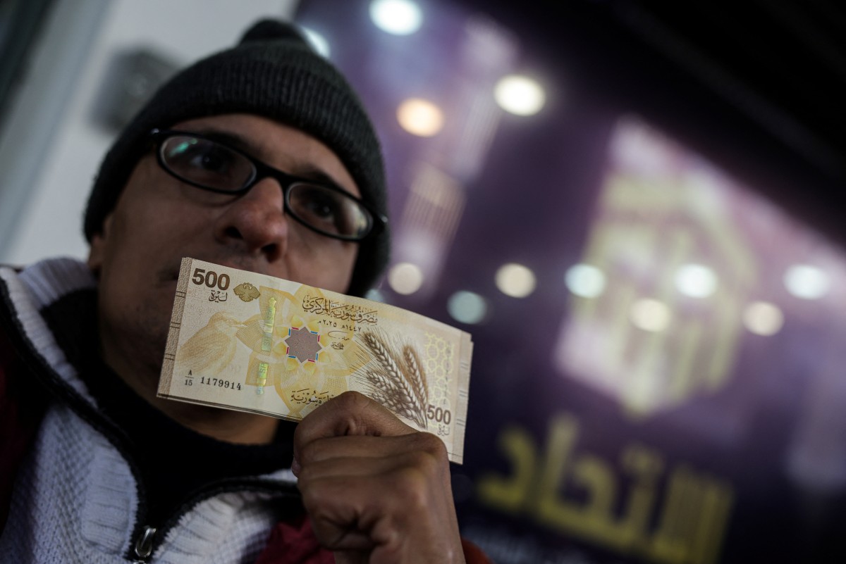 مواطن سوري يستعرض ورقة نقدية جديدة أصدرها ووزعها البنك المركزي في دمشق. (أ ف ب)
