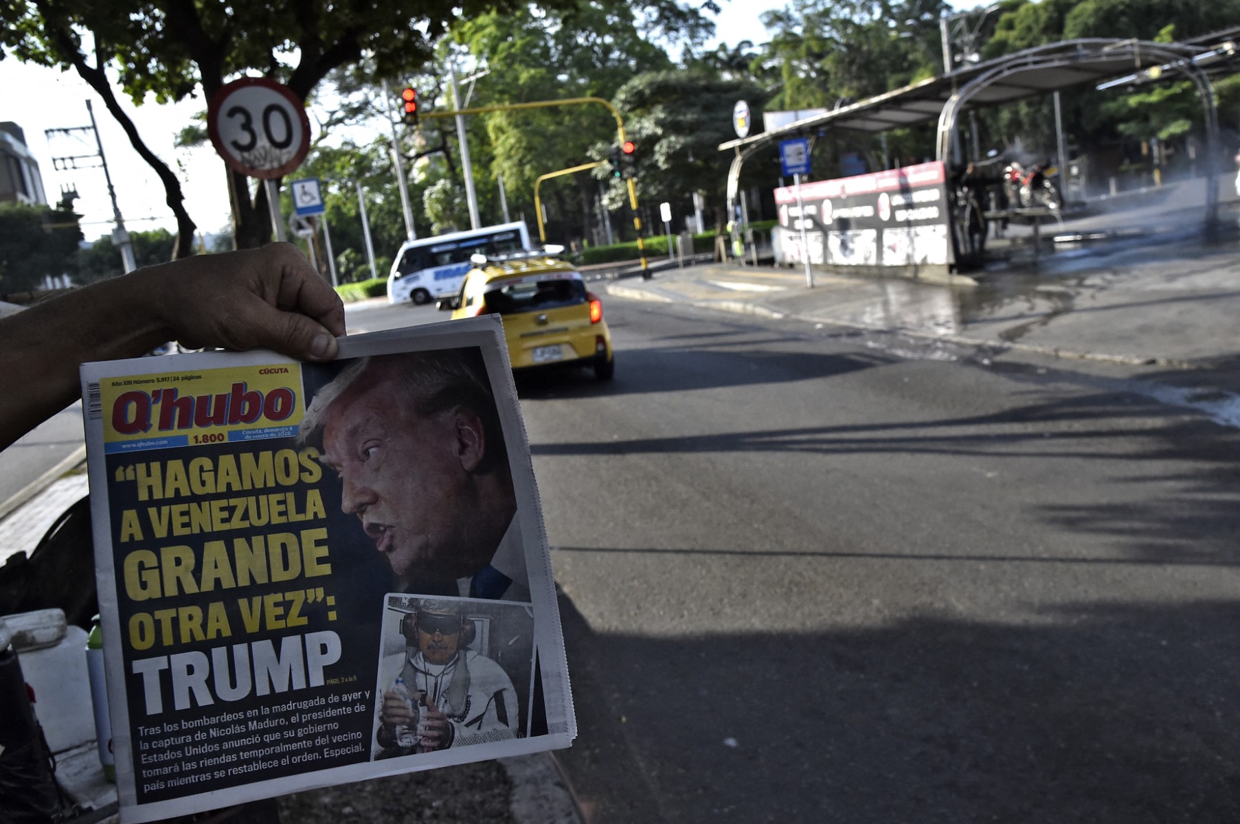 رجل يعرض الصفحة الأولى من صحيفة مكتوب عليها: لنجعل فنزويلا عظيمة مرة أخرى، في كولومبيا. (أ ف ب)