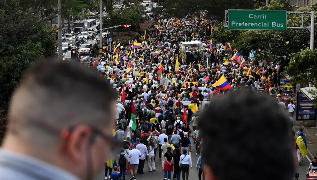الناس يلوحون بأعلام كولومبيا أثناء مشاركتهم في مسيرة من أجل السيادة والديموقراطية ضد تهديدات ترامب للرئيس الكولومبي (أ ف ب)