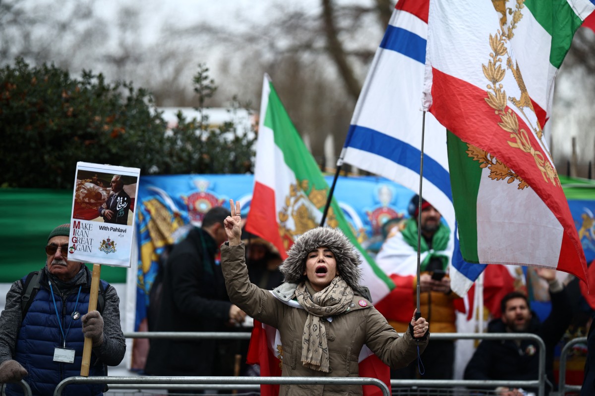 رفع متظاهرون العلم الإيراني الذي يحمل شعار الأسد والشمس قبل ثورة 1979، إلى جانب الأعلام الإسرائيلية، خلال تجمع أمام السفارة الإيرانية في لندن. (أ ف ب)
