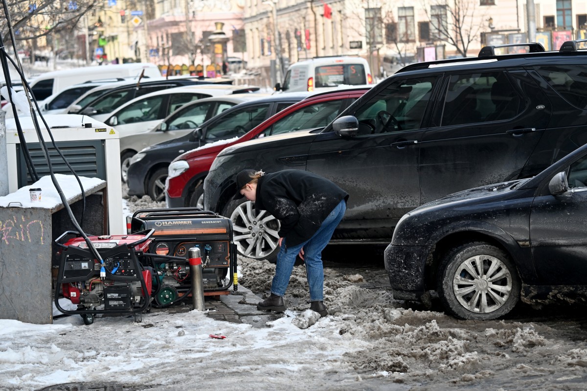امرأة تتحكم في مولدات الكهرباء التي تعمل خارج مقهى خلال ساعات انقطاع التيار الكهربائي في وسط كييف (أ ف ب)
