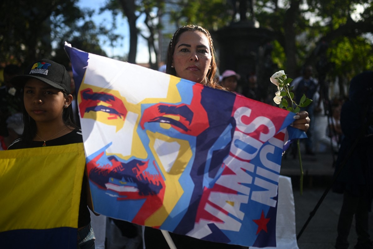 امرأة تحمل علماً عليه صورة مادورو خلال مسيرة لدعمه في ساحة بوليفار في كاراكاس. (أ ف ب)
