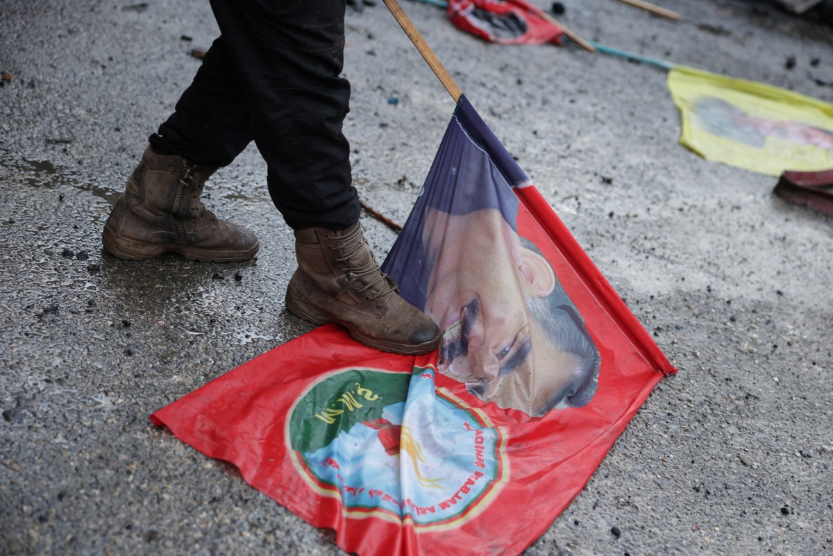 جندي سوري يدوس على علم يحمل صورة الزعيم الكردي المسجون عبد الله أوجلان، في حي الشيخ مقصود في حلب. (أ ف ب)
