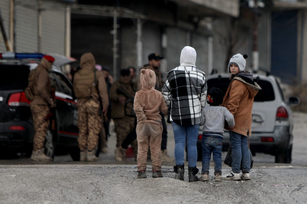 أطفال يقفون يشاهدون قوات الأمن السورية بعد وقف إطلاق النار الذي أنهى عدة أيام من القتال بين قوات الأمن السورية والمقاتلين الأكراد في حي الشيخ مقصود ذي الأغلبية الكردية، شمال مدينة حلب. (أ ف ب)