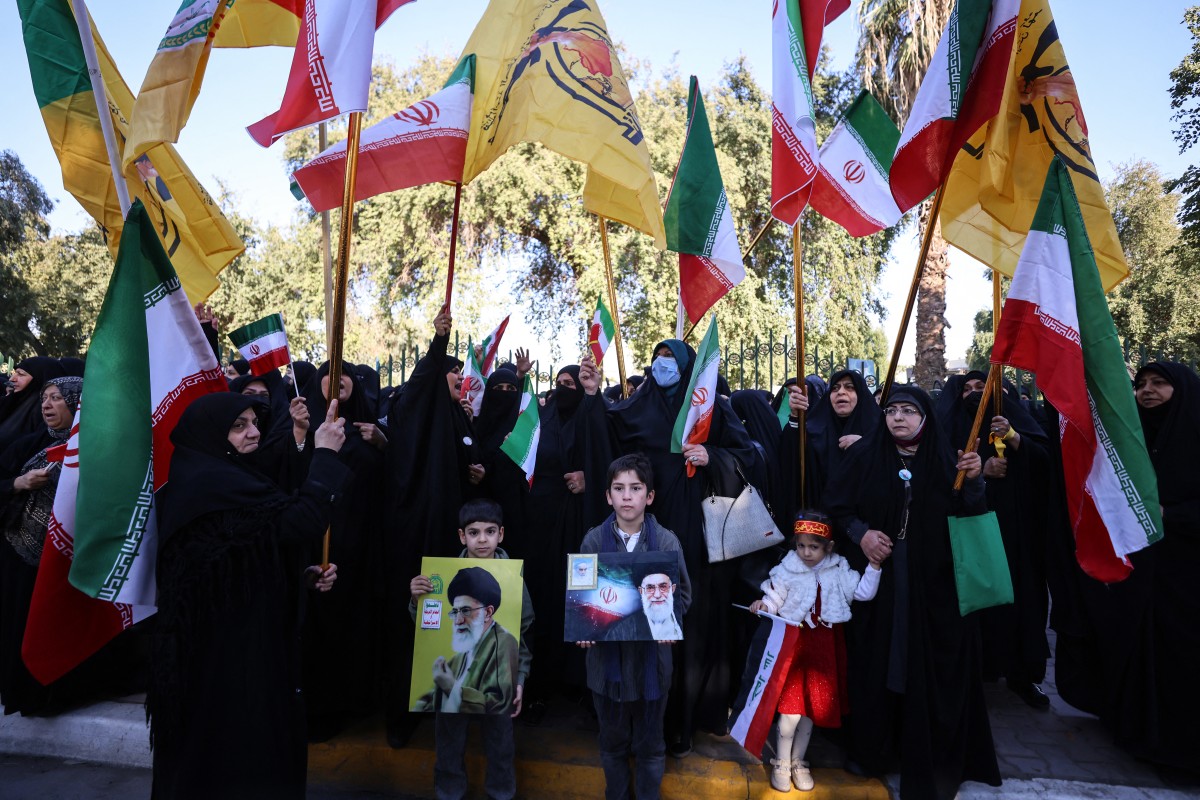 عراقيون يحرقون أعلام الولايات المتحدة وإسرائيل قرب السفارة الإيرانية في بغداد دعمًا لإيران. (أ ف ب)