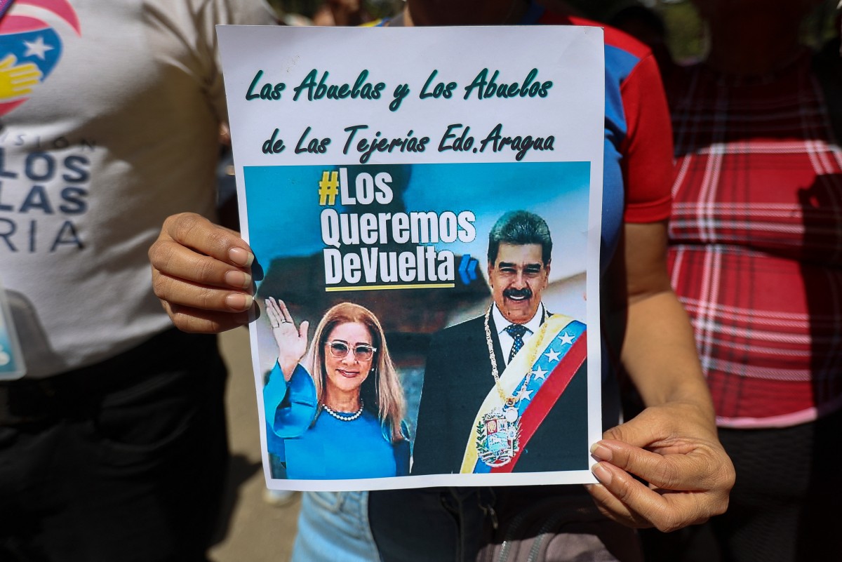 امرأة ترفع لافتة خلال مظاهرة للمطالبة بالإفراج عن الرئيس الفنزويلي نيكولاس مادورو وزوجته سيليا فلوريس في كاراكاس. (أ ف ب)