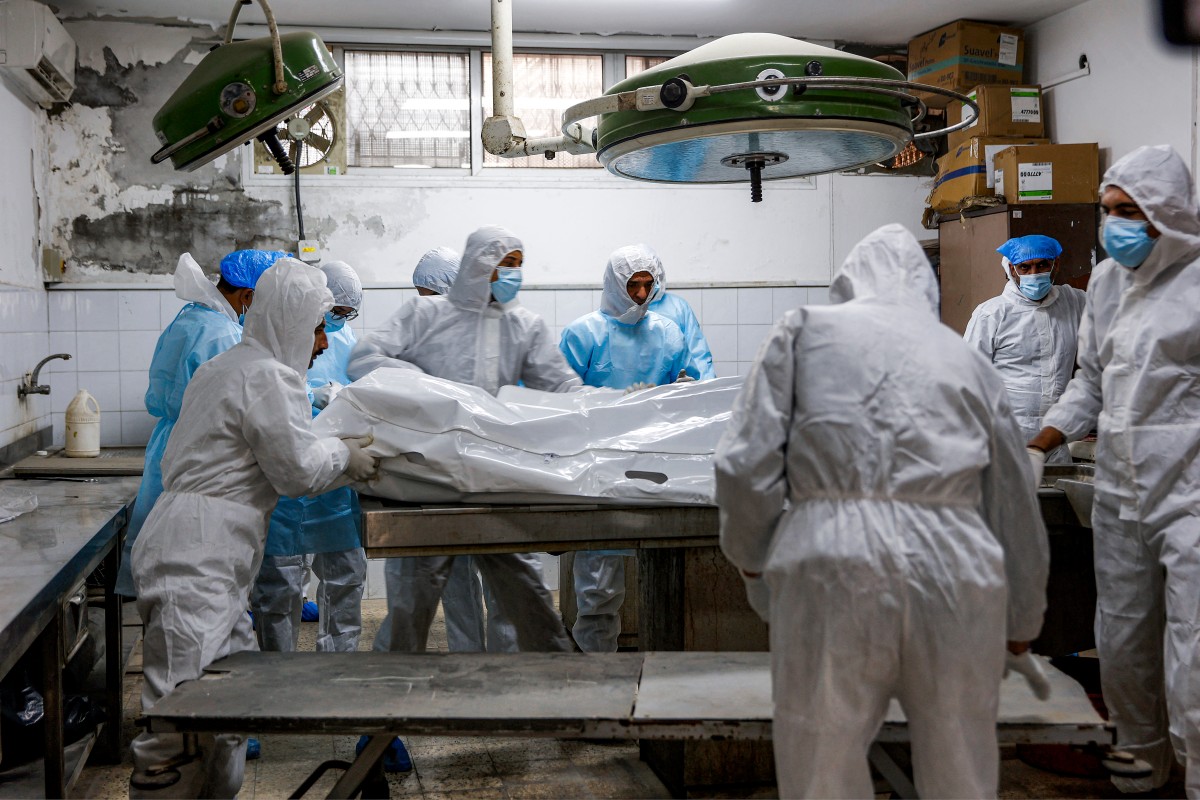 خبراء الطب الشرعي يفحصون جثث الفلسطينيين التي أعادتها إسرائيل في اليوم السابق، كجزء من اتفاق وقف إطلاق النار في غزة. (أ ف ب)