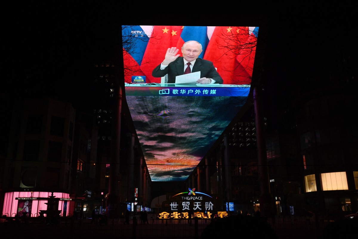 الرئيس الروسي فلاديمير بوتين يلوح للرئيس الصيني شي جين بينغ على شاشة كبيرة خارج مركز تجاري في بكين. (أ ف ب)