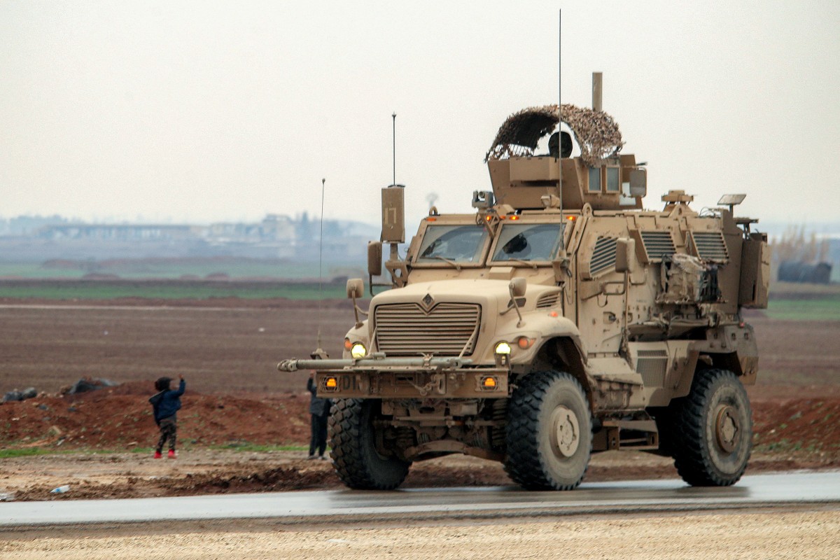 طفلان يلوحان لمدرعة أميركية في محافظة الحسكة، شمال شرق سوريا. (أ ف ب)