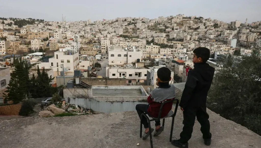 فتيان فلسطينيون وتبدو أمامهم مدينة الخليل في الضفة الغربية. (أ ف ب)