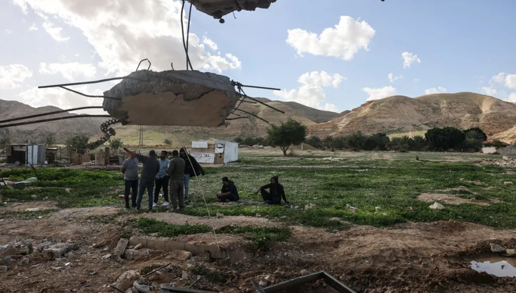 فلسطينيون يقفون أمام أنقاض منزل قيل إن مستوطنين إسرائيليين قاموا بهدمه في اليوم السابق في قرية في ضواحي أريحا في الضفة الغربية، في 11 فبراير 2026. (أ ف ب)