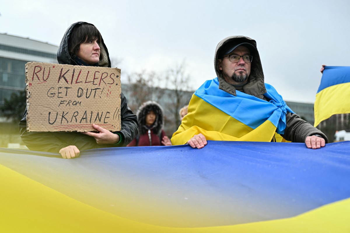 متظاهرون يحملون لافتة وأعلام أوكرانية أثناء جولة جديدة من المحادثات بين المفاوضين الروس والأوكرانيين والأميركيين بهدف إيجاد حل لأربع سنوات من القتال في أوكرانيا، في جنيف. (أ ف ب) 