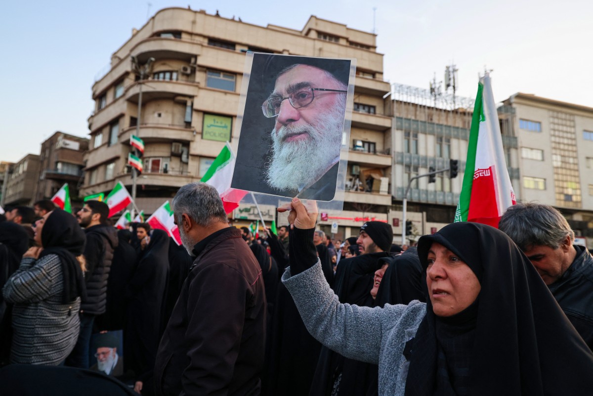 A man holds a poster of Iran's Supreme Leader Ali Khamenei while joining other mourners in a square in Tehran. (AFP)